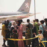 Crowd of people waiting outside to board airplane in Afghanistan